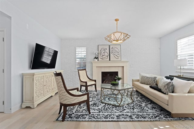 living area featuring brick wall, a tiled fireplace, and light wood-style flooring