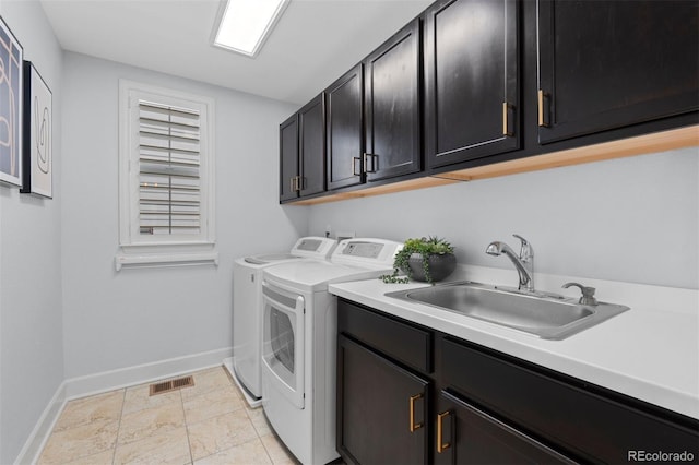 washroom featuring cabinet space, visible vents, baseboards, washing machine and dryer, and a sink