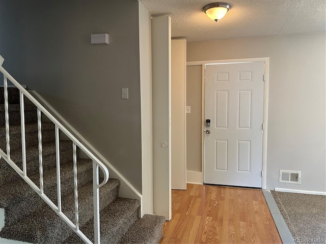 12252 Elmendorf Pl, Denver, CO 80239 - entryway with wood finished floors, stairway, and a textured ceiling