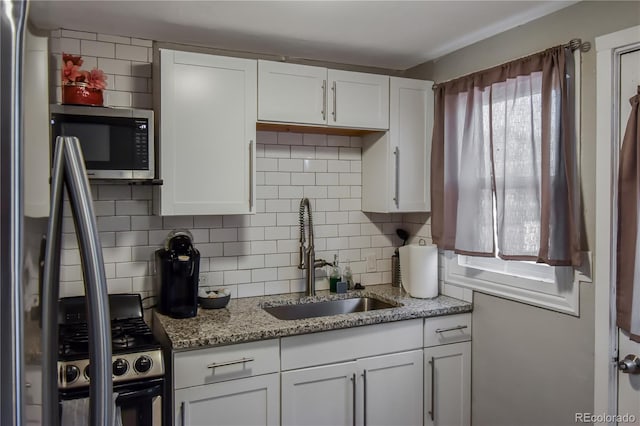 kitchen with sink, light stone countertops, white cabinetry, and stainless steel appliances