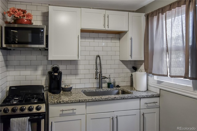 kitchen featuring sink, gas range, white cabinetry, and light stone countertops