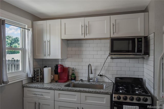 kitchen featuring white cabinetry, gas range, sink, and decorative backsplash