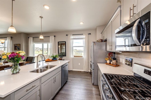 kitchen with stainless steel appliances, a sink, light countertops, dark wood-style floors, and recessed lighting
