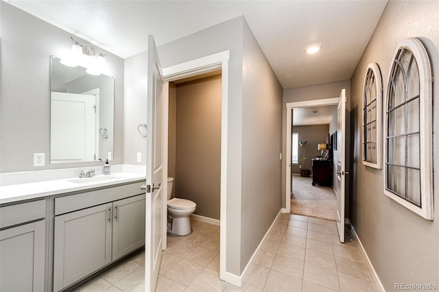 bathroom featuring toilet, tile patterned floors, vanity, and baseboards