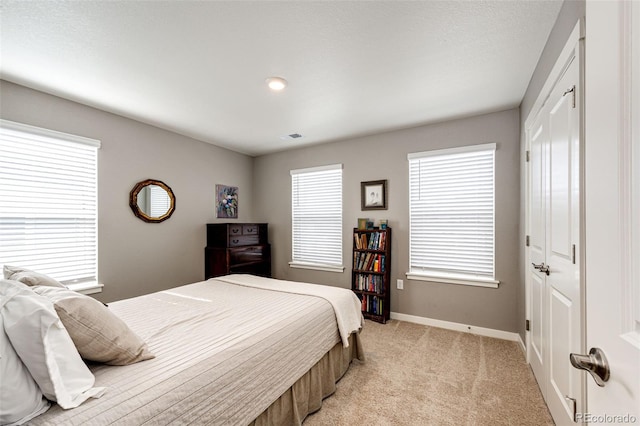 bedroom featuring baseboards, light colored carpet, and a closet