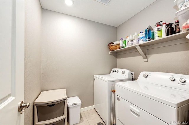 laundry room with washing machine and clothes dryer, light tile patterned floors, and baseboards