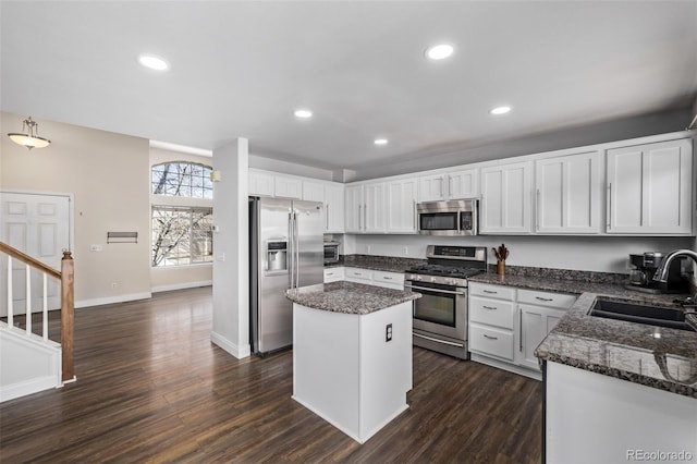 kitchen with sink, dark wood-type flooring, white cabinetry, stainless steel appliances, and a center island