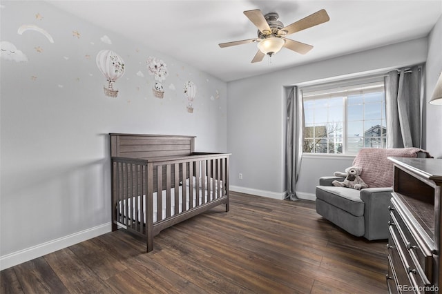 bedroom with dark hardwood / wood-style flooring, a nursery area, and ceiling fan