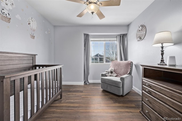 bedroom with a nursery area, ceiling fan, and dark hardwood / wood-style floors