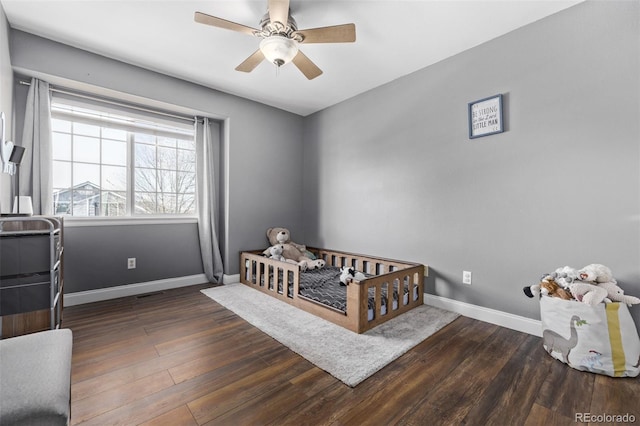 bedroom featuring a crib, dark hardwood / wood-style floors, and ceiling fan