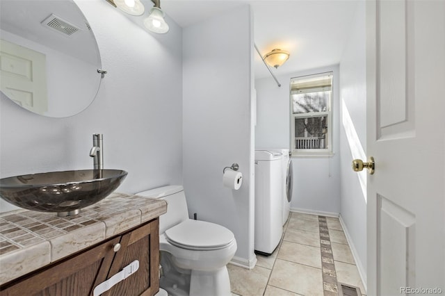 bathroom featuring tile patterned floors, toilet, washing machine and dryer, and vanity