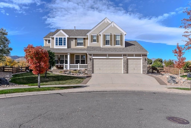 traditional home with concrete driveway, a porch, roof with shingles, and fence