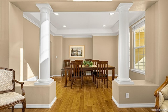 dining area featuring ornamental molding, decorative columns, light wood-style flooring, and baseboards