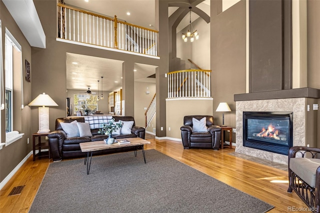 living room with a tile fireplace, stairway, baseboards, and wood finished floors