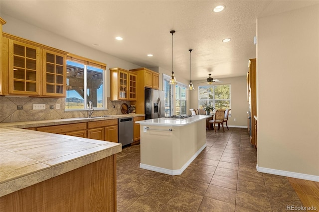 kitchen featuring a center island, decorative backsplash, appliances with stainless steel finishes, glass insert cabinets, and a sink