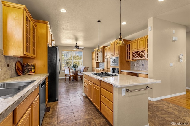 kitchen featuring light countertops, appliances with stainless steel finishes, a kitchen island, and decorative backsplash