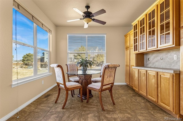 dining area with ceiling fan, baseboards, and a textured ceiling