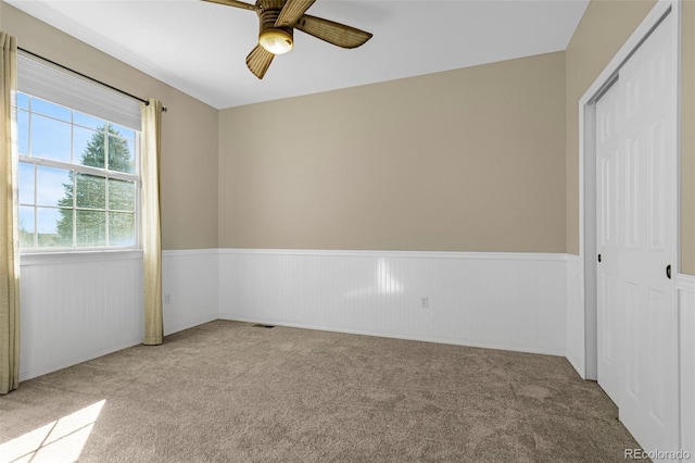 unfurnished bedroom with ceiling fan, carpet floors, and wainscoting