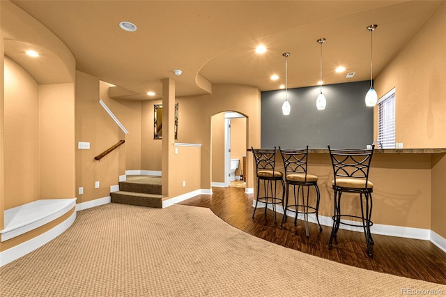 bar with arched walkways, baseboards, wood finished floors, and recessed lighting