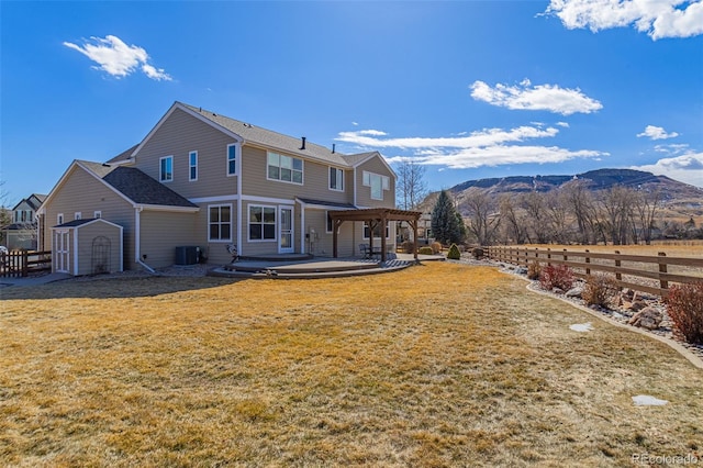 rear view of property with a pergola, fence, a yard, a mountain view, and central AC