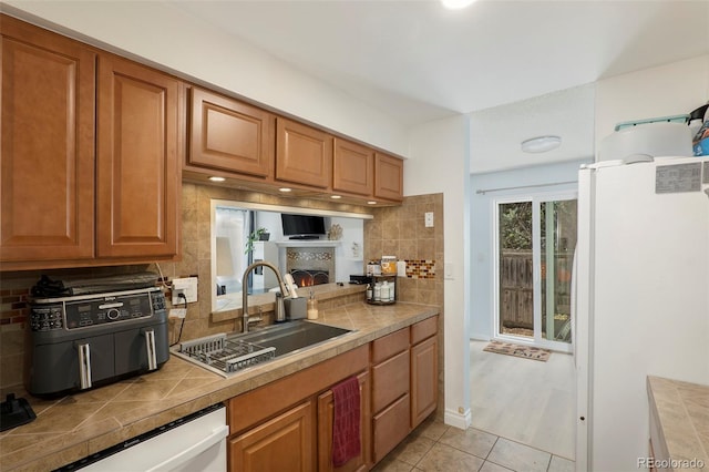 13 Nome Way Unit A, Aurora, CO 80012 - kitchen with brown cabinets, a sink, white appliances, light tile patterned floors, and backsplash