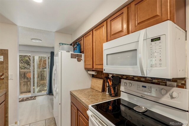 13 Nome Way Unit A, Aurora, CO 80012 - kitchen with brown cabinets, backsplash, and white appliances