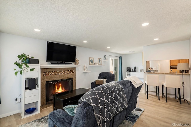 13 Nome Way Unit A, Aurora, CO 80012 - living room featuring recessed lighting, a textured ceiling, a tiled fireplace, and light wood-type flooring