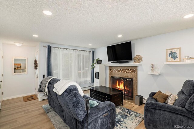 13 Nome Way Unit A, Aurora, CO 80012 - living room featuring light wood-style floors, a fireplace, a textured ceiling, recessed lighting, and a baseboard heating unit
