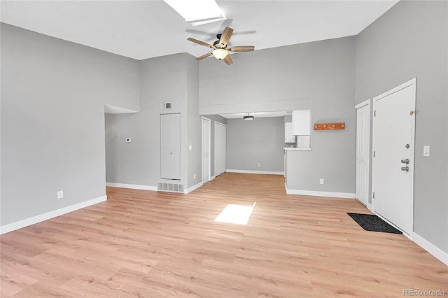 entryway with ceiling fan, high vaulted ceiling, baseboards, and light wood-style floors