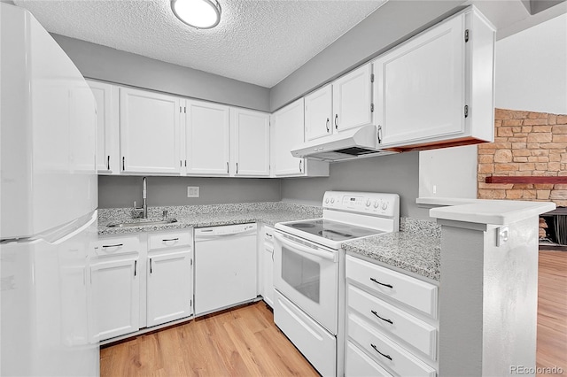 kitchen with white appliances, under cabinet range hood, a sink, light wood-type flooring, and a textured ceiling