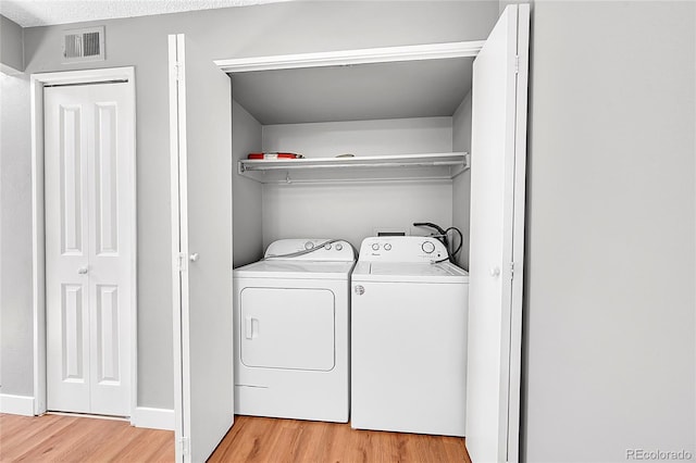 laundry area featuring light wood-type flooring, washer and clothes dryer, and baseboards