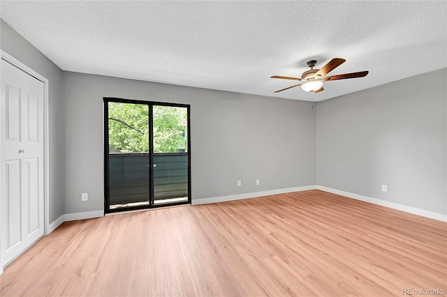spare room featuring light wood-style floors, a ceiling fan, a textured ceiling, and baseboards