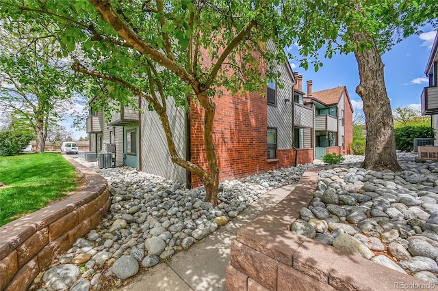 view of side of home featuring central AC and brick siding