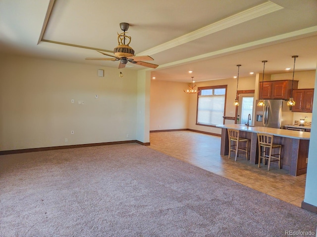 kitchen featuring ceiling fan with notable chandelier, sink, a breakfast bar area, stainless steel refrigerator with ice dispenser, and light carpet