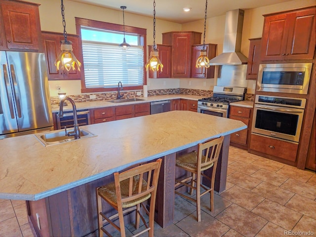 kitchen with a kitchen bar, sink, a center island, appliances with stainless steel finishes, and wall chimney range hood