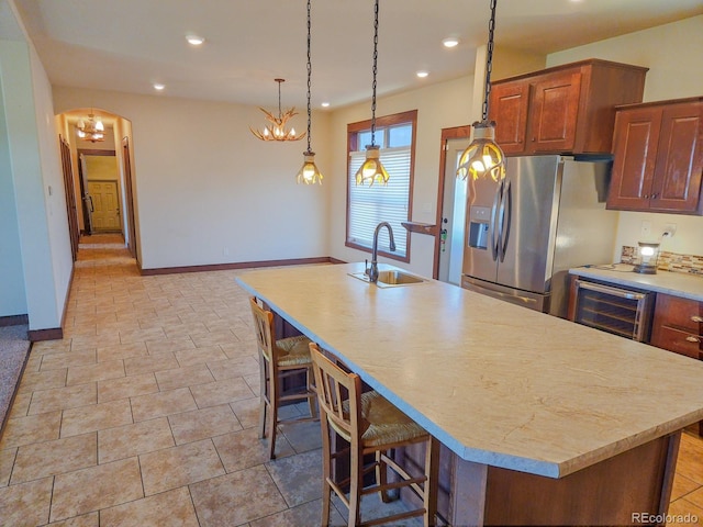 kitchen with wine cooler, stainless steel fridge, sink, and a center island with sink