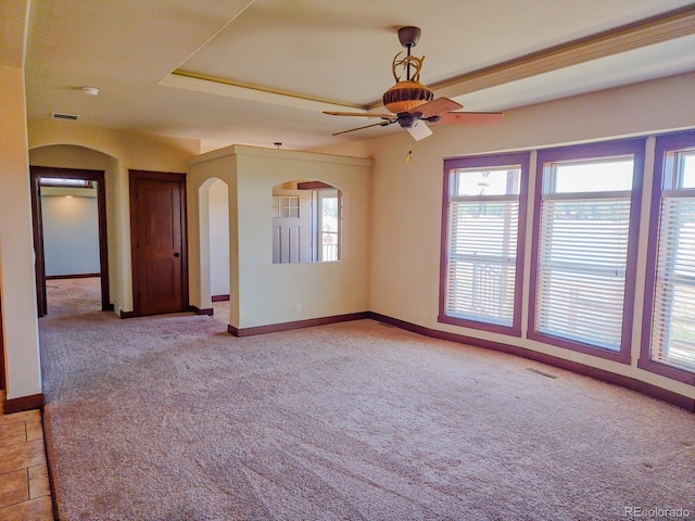 carpeted spare room with ceiling fan and a tray ceiling