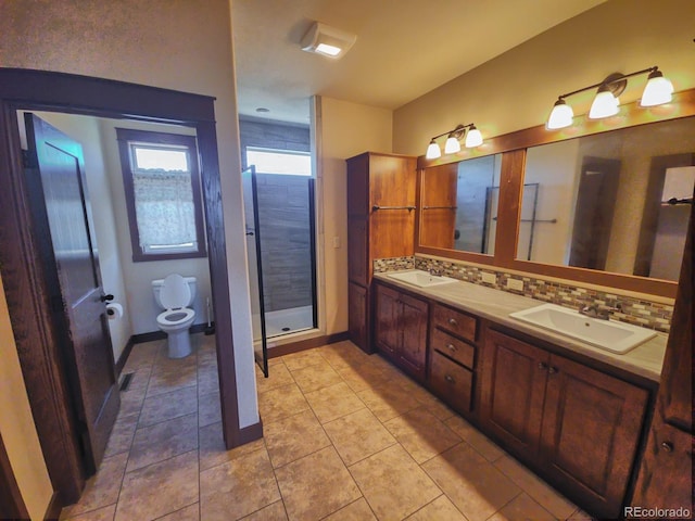 bathroom with tile patterned floors, toilet, a shower, vanity, and decorative backsplash