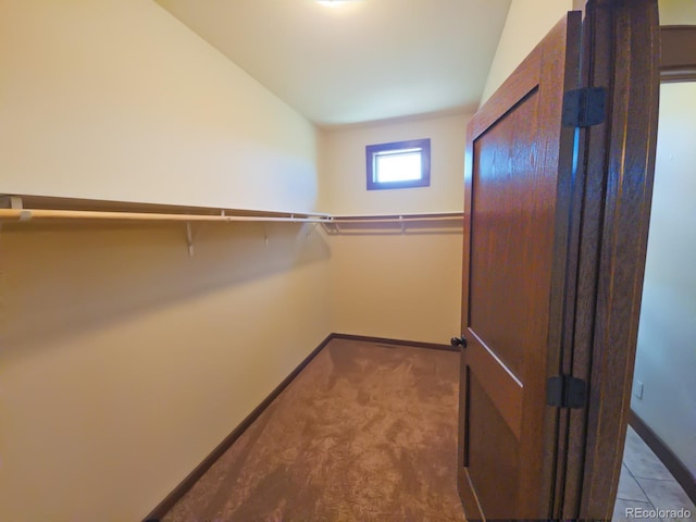 walk in closet with vaulted ceiling and carpet flooring