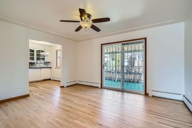 interior space with light wood finished floors, ceiling fan with notable chandelier, baseboards, and a baseboard radiator