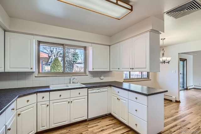 kitchen featuring visible vents, a sink, dark countertops, baseboard heating, and dishwasher