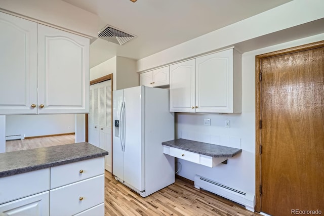 kitchen featuring visible vents, dark countertops, white refrigerator with ice dispenser, white cabinets, and a baseboard radiator