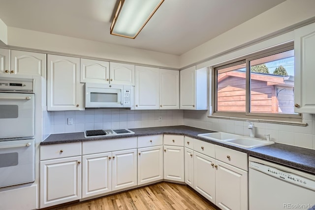 kitchen with a sink, white appliances, and white cabinets