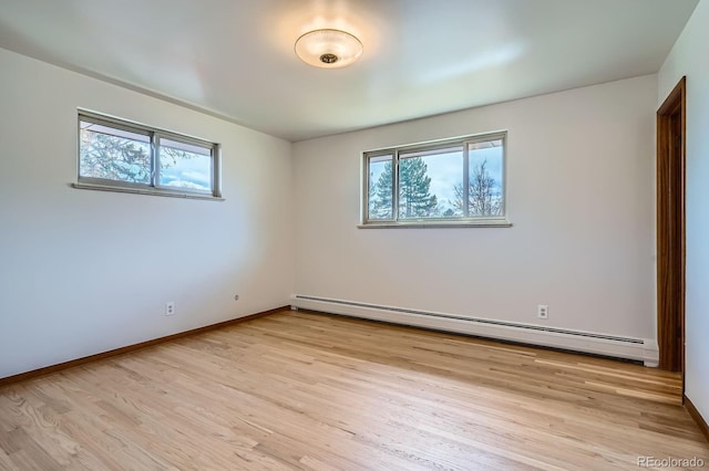 empty room with a baseboard radiator, baseboards, and light wood-style floors