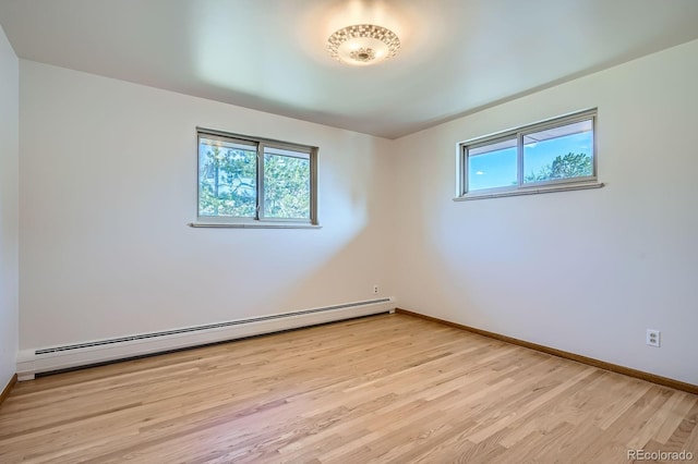 spare room featuring light wood finished floors, plenty of natural light, baseboards, and baseboard heating