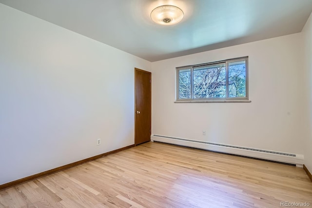 empty room with baseboard heating, baseboards, and light wood-style floors