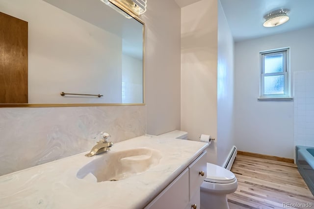 full bath featuring vanity, wood finished floors, a baseboard radiator, toilet, and a bathtub