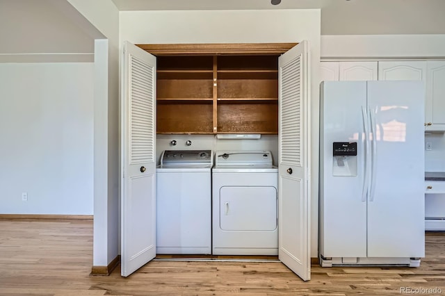 clothes washing area with laundry area, light wood-style floors, baseboard heating, and washing machine and clothes dryer