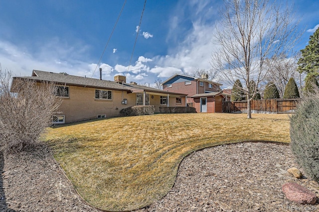 rear view of property with an outdoor structure, a yard, fence, and brick siding