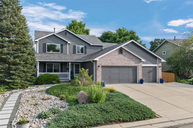 2066 Amber Ct, Erie, CO 80516 - traditional home with an attached garage, a porch, driveway, brick siding, and a shingled roof